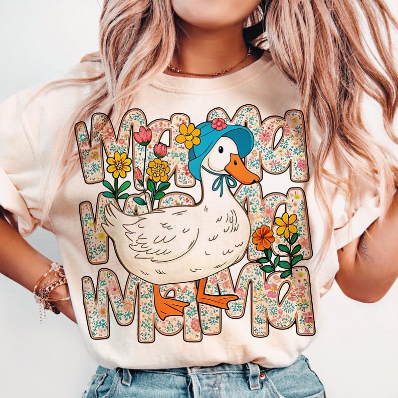 May include: A white t-shirt with a cartoon duck wearing a blue hat and surrounded by flowers. The text "Mama Mama Mama" is printed on the shirt.