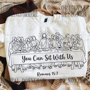 May include: White crewneck sweatshirt featuring a black and white illustration of the Last Supper. The text "You Can Sit With Us" and "Romans 15:7" are printed below the image. The sweatshirt has a simple, classic design.