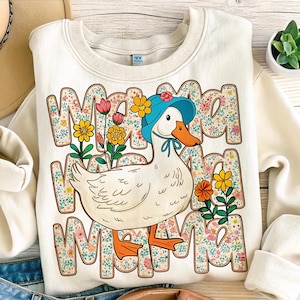May include: A white sweatshirt with a cartoon duck wearing a blue hat and surrounded by flowers. The text "Mama Mama Mama" is printed on the sweatshirt.