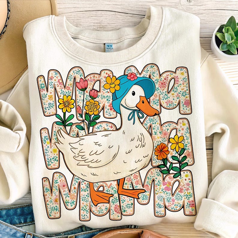 May include: A white sweatshirt with a cartoon duck wearing a blue hat and surrounded by flowers. The text "Mama Mama Mama" is printed on the sweatshirt.