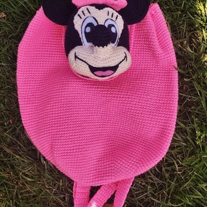 May include: Pink crocheted backpack with a Minnie Mouse face. The backpack measures 13 inches tall and 11 inches wide.