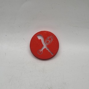 Puede incluir: Una ficha circular roja con una silueta blanca de una vaina de guisante y un cuchillo curvo cruzándose.