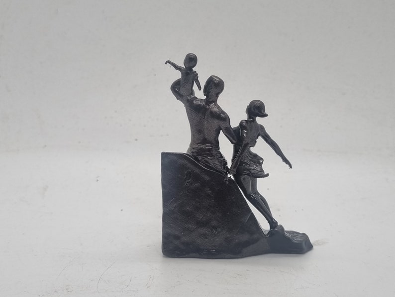 May include: A black metal sculpture of a family. The father is holding a child up in the air, while the mother is walking beside him. The sculpture is on a black base.