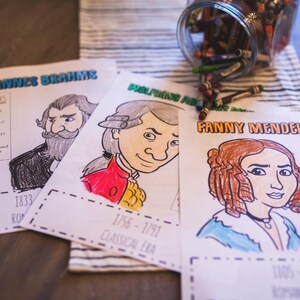 Puede incluir: P&aacute;ginas para colorear con retratos de Johannes Brahms, Wolfgang Amadeus y Fanny Mendelssohn, con texto que indica sus nombres y &eacute;pocas. Un tarro de crayones es visible en el fondo. Las p&aacute;ginas est&aacute;n parcialmente coloreadas.