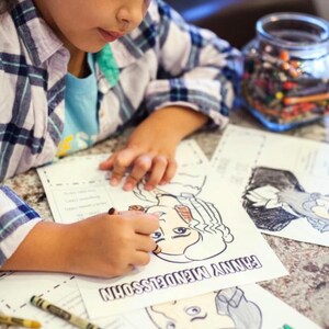 Puede incluir: Un ni&ntilde;o colorea un dibujo en blanco y negro de una persona con el texto "FANNY MENDELSSOHN" en la p&aacute;gina. Creyones y un tarro de l&aacute;pices de colores est&aacute;n cerca. El ni&ntilde;o lleva una camisa a cuadros.