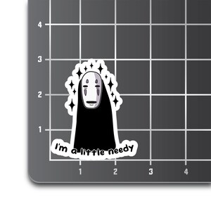 May include: A white sticker with a black and white cartoon character with a mask and the text "I'm a little needy".