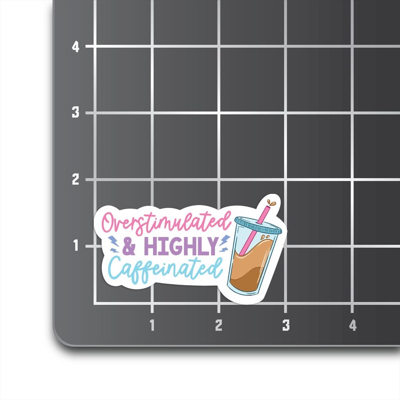 May include: A white sticker with a pink, blue, and purple graphic of a coffee cup with a straw and the text "Overstimulated & HIGHLY Caffeinated".