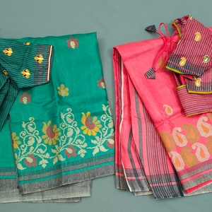 May include: Two folded saris with matching embroidered blouses. The sari on the left is teal green with a floral pattern and the sari on the right is pink with a paisley pattern.