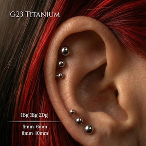 May include: A white ceramic mug with a black handle and the text "But First, Coffee" in a black, bold font. The mug is on a white surface. The mug is approximately 10 cm tall.