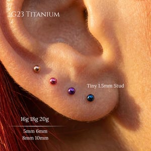 May include: Four G23 titanium ball stud earrings in gold, pink, purple, and blue. Each tiny 1.5mm stud is displayed in a row. Text on the image indicates 16g, 18g, 20g gauges and 5mm, 6mm, 8mm, 10mm lengths for these G23 titanium jewelry pieces.