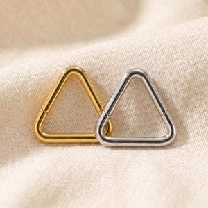 Peut inclure: Deux anneaux triangulaires, l'un dor&eacute; et l'autre argent&eacute;, avec une finition polie. Chaque anneau est dot&eacute; d'un m&eacute;canisme &agrave; charni&egrave;re, permettant &agrave; la forme triangulaire de s'ouvrir et de se fermer pour une insertion facile dans un piercing.