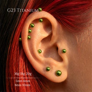 Könnte beinhalten: Ohrschmuck aus G23 Titan mit mehreren kleinen, glänzenden, metallisch grünen Kugelsteckern. Der Text G23 TITANIUM, 16g 18g 20g sowie 5mm 6mm 8mm 10mm ist auf dem Bild zu sehen und gibt das Material, die Stärken und die Längen an.