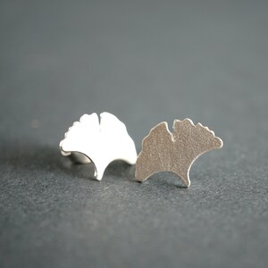 Op de afbeelding: Een paar zilveren oorbellen in de vorm van ginkgo bladeren. De oorbellen zijn eenvoudig en elegant en zouden een geweldig cadeau zijn voor iemand die van de natuur houdt.