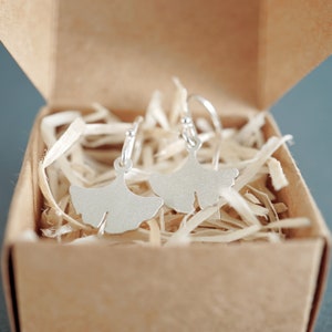 May include: A pair of silver earrings shaped like ginkgo leaves, displayed in a small cardboard box filled with shredded paper.