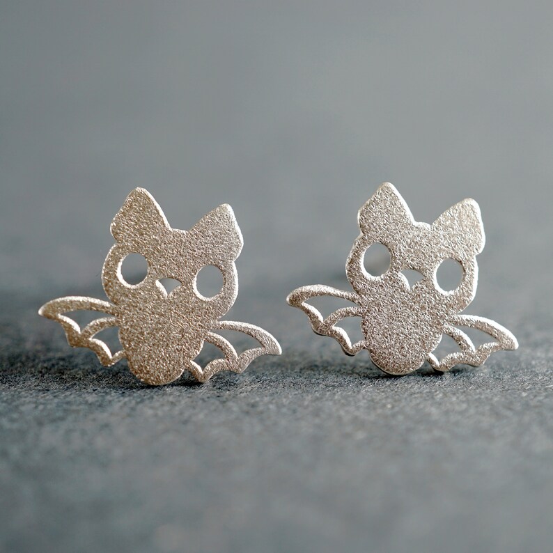 Peut inclure: Une paire de boucles d'oreilles en argent en forme de chauve-souris. Les chauves-souris sont d&eacute;coup&eacute;es et ont une finition textur&eacute;e.