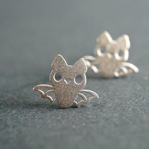 Peut inclure: Une paire de boucles d'oreilles en argent en forme de chauve-souris. Les chauves-souris ont des ailes et des yeux d&eacute;coup&eacute;s.