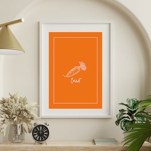 May include: A white line drawing of a carrot on an orange background with the word "Carrot" written below the drawing. The image is framed in a white frame and is hanging on a white wall.