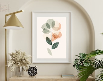 May include: A framed print of a stylized abstract floral design with green and peach colored leaves. The print is hanging on a white wall above a wooden shelf with a clock and a vase of dried flowers.
