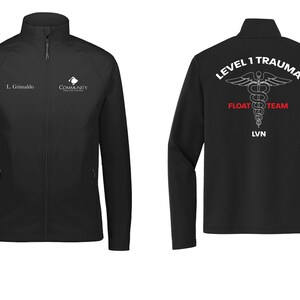 May include: Black softshell jacket with a zipper closure. The left side of the jacket has a white embroidered logo that says "Community Health System" and "L. Grimaldo". The right side of the jacket has a white embroidered logo that says "Level 1 Trauma Float Team LVN" with a caduceus symbol.