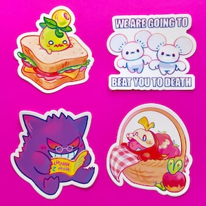 Op de afbeelding: Vier kleurrijke stickers met cartoonfiguren. De eerste sticker toont een groen personage met een geel gezicht op een sandwich. De tweede sticker toont twee witte muizen met roze oren en roze neuzen. De tekst op de sticker luidt "We are going to beat you to death". De derde sticker toont een paars personage met een rood gezicht en een bril die een boek leest. De tekst op het boek luidt "How 2 haunt". De vierde sticker toont een rood personage met een geel gezicht in een mand met een rood-wit geruit tafelkleed.