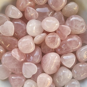 Pode incluir: Uma cole&ccedil;&atilde;o de pedras de quartzo rosa polidas em v&aacute;rias formas e tamanhos. As pedras variam em cor do rosa p&aacute;lido a um tom rosa mais profundo, com algumas pe&ccedil;as em forma de cora&ccedil;&atilde;o.