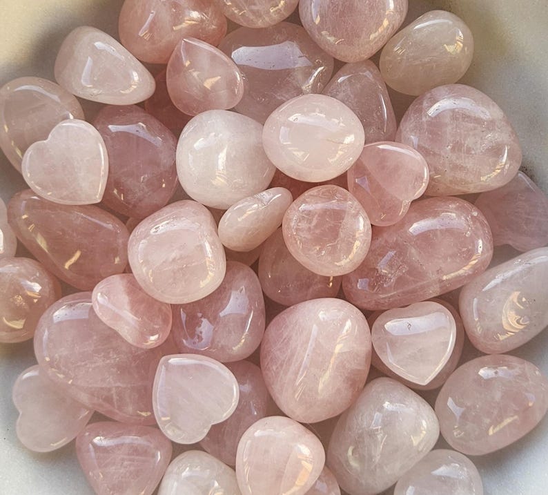 Pode incluir: Uma cole&ccedil;&atilde;o de pedras de quartzo rosa polidas em v&aacute;rias formas e tamanhos. As pedras variam em cor do rosa p&aacute;lido a um tom rosa mais profundo, com algumas pe&ccedil;as em forma de cora&ccedil;&atilde;o.