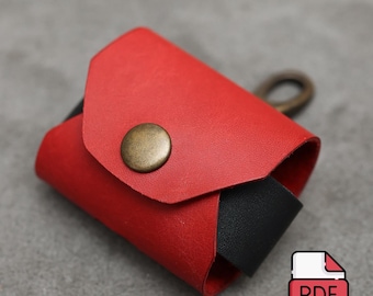 May include: A small, rectangular red leather case with a black interior lining. The case features a front flap secured by a circular, antique brass-colored metal snap button and includes a matching brass-colored metal ring attachment on the back.