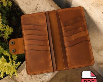 May include: A tan leather bifold wallet featuring multiple vertical card slots on both interior panels and a side tab closure secured with two metal snap buttons. The wallet has visible stitching along the edges and a smooth, matte finish.