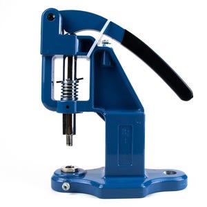 May include: A blue manual grommet press machine featuring a vertical metal plunger with a coiled spring mechanism, a long handle with a black grip, and a sturdy base with a circular die insert for securing fasteners into fabric or leather materials.