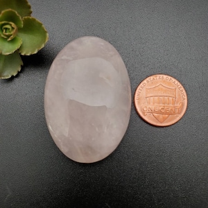 Peut inclure: Un cristal de quartz rose de forme ovale de couleur rose pâle, d'environ la taille d'une pièce de un centime d'euro.