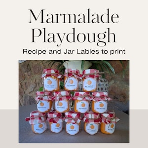 Peut inclure: Une pile de petits pots en verre remplis de pâte à modeler à la marmelade orange. Les pots sont décorés de tissu à carreaux rouges et blancs et de ficelle. Les étiquettes sur les pots disent "marmelade".