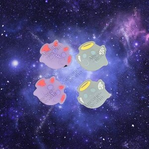 Può includere: Quattro ciondoli decorativi per scarpe a forma di corpi celesti. Due sono lavanda con dettagli rossi, e due sono grigi con dettagli gialli. Ogni ciondolo ha il testo "Arcane Realm". Lo sfondo è una galassia stellata.