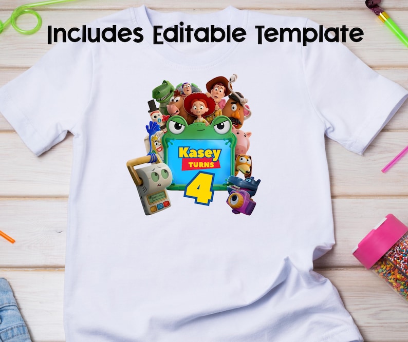 May include: A white short-sleeved t-shirt featuring a graphic print of various animated toy characters surrounding a green frog-shaped frame. The frame contains the text Kasey Turns 4 in yellow and red lettering. The design includes multiple colourful figures.