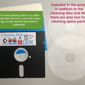 May include: A black floppy disk with a blue label that says "Cleaning Disk." The label has logos for Commodore, Philips, Atari, and IBM. The disk is accompanied by two white cleaning discs with a central hole.