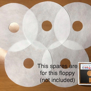 May include: Five white cleaning disks for floppy disks. The text "This spares are for this floppy (not included)" is written below the disks. A cleaning disk for a floppy disk is shown in the lower right corner of the image.