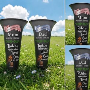 May include: Black memorial vase with a flared top, featuring the text "In Loving Memory" on a banner. The vase includes the name "Mum" or "Dad", dates, and the phrase "Robins appear when Loved Ones are near", with a robin illustration.