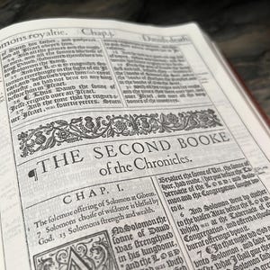 May include: Open book with text from "The Second Booke of the Chronicles." The page is aged with a decorative border. The text is in black ink on off-white paper. The book is open to Chapter I.