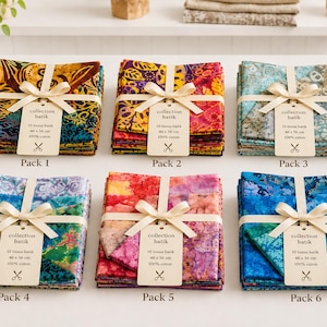 Peut inclure: Six piles de carrés de tissu batik pliés, chacun attaché avec un ruban crème et une étiquette marquée collection batik 10 tissus batik 46 x 56 cm 100% coton. Les motifs des tissus présentent divers designs floraux et abstraits aux couleurs vives.