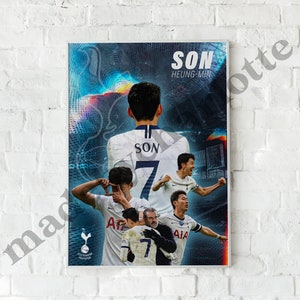 Op de afbeelding: Een poster met een collage van afbeeldingen van een voetballer, Heung-Min Son, die een wit en donkerblauw voetbalshirt draagt met nummer 7 op de rug. De poster heeft een blauwe achtergrond met een kleurrijk abstract ontwerp en de tekst "SON HEUNG-MIN" bovenaan.