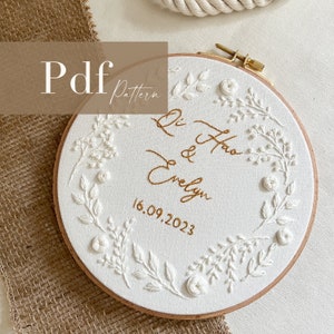 Puede incluir: Aro de bordado blanco con un diseño floral y el texto "Li Hao & Evelyn 16.09.2023" en hilo dorado.