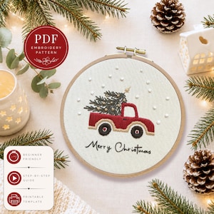 Pode incluir: Um bastidor de bordado com um design de Natal. Apresenta uma carrinha vermelha a transportar uma árvore de Natal, com as palavras "Merry Christmas" bordadas por baixo. O desenho está sobre um tecido creme. A imagem inclui o texto "PDF Embroidery Pattern".
