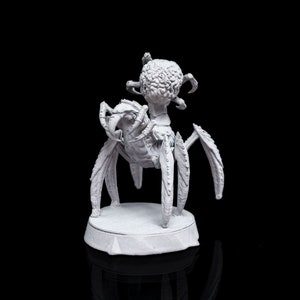 Könnte beinhalten: Eine weiß bemalte Miniatur einer spinnenartigen Kreatur mit einem runden, gehirnartigen Kopf. Die Kreatur hat acht Beine und steht auf einem runden Sockel.