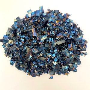 Könnte beinhalten: Ein Haufen schimmernder blauer und schwarzer Metallkonfetti. Das Konfetti besteht aus kleinen, unregelmäßigen Metallstücken, die in verschiedene Formen geschnitten wurden.