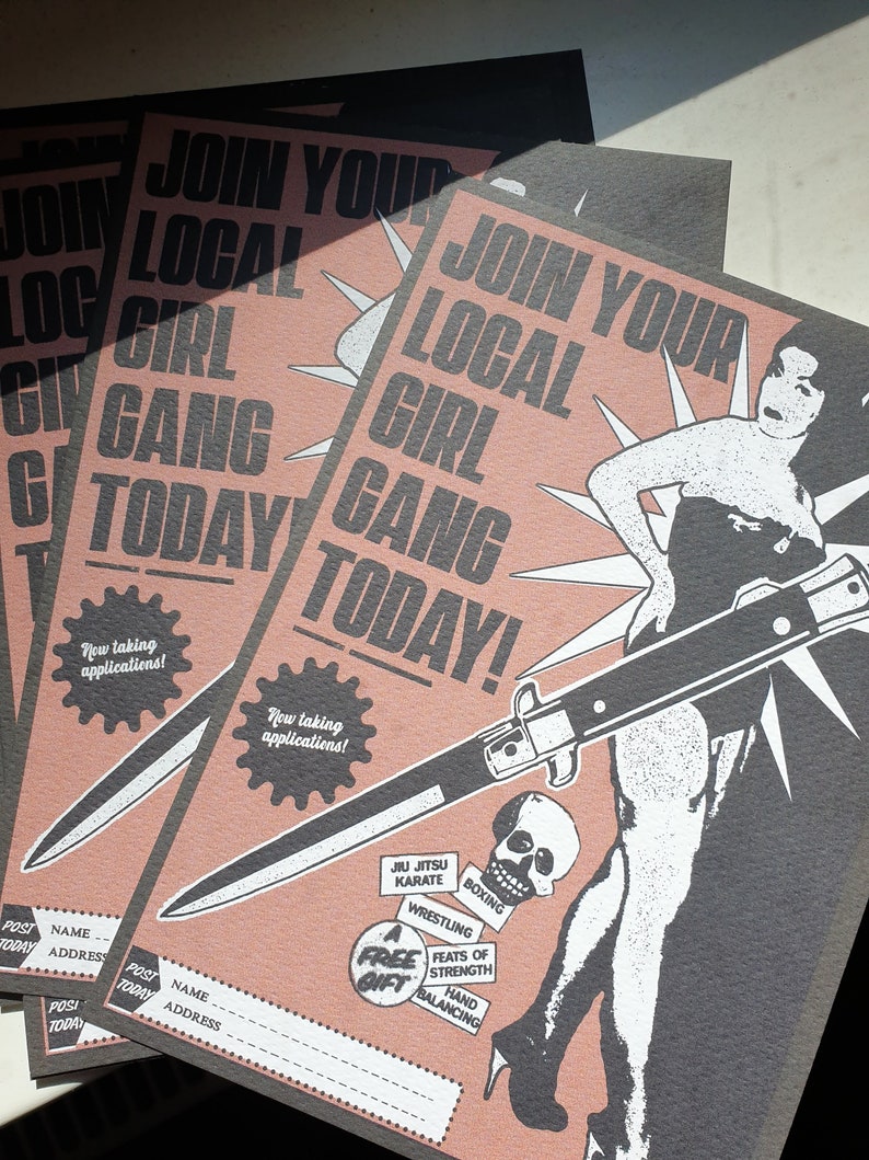 Puede incluir: Un p&oacute;ster rosa y negro con el texto "&Uacute;nete a tu pandilla de chicas local hoy!" y una ilustraci&oacute;n de una mujer sosteniendo un cuchillo. El p&oacute;ster tambi&eacute;n incluye una lista de actividades, que incluyen Jiu Jitsu, Karate, Boxeo, Lucha y haza&ntilde;as de fuerza y equilibrio de manos.