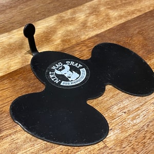 Puede incluir: Bandeja de metal negro con una forma &uacute;nica y un asa curvada. La bandeja tiene una pegatina circular con el texto "MAG TRAY" y un gr&aacute;fico. Tambi&eacute;n es visible la direcci&oacute;n del sitio web "www.minimagtray.co.uk".