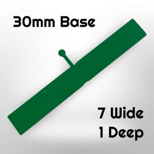 May include: A green rectangular object with a small circular knob and the text "30mm Base", "7 Wide", and "1 Deep". The object is a dark green color and appears to be made of metal or plastic.