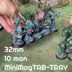 May include: Miniature fantasy figures in blue, gold, and red are displayed on a gaming surface. The figures are mounted on 32mm bases. The text "10 man" and "MiniMagTAB-TRAY" are visible. The figures are part of a 10-man unit.
