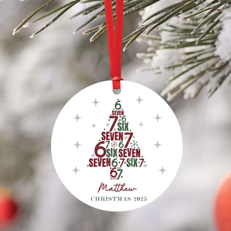 K&ouml;nnte beinhalten: Ein runder, wei&szlig;er Weihnachtsschmuck mit rotem Band. Der Schmuck zeigt ein Weihnachtsbaumdesign aus Zahlen und dem Wort "SEVEN" in Gr&uuml;n und Rot. Der Name "Matthew" und das Jahr "CHRISTMAS 2025" sind unten aufgedruckt.
