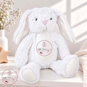 May include: A white plush rabbit toy with long floppy ears and a soft textured finish. The center of the chest features a circular graphic with a gift box icon, three small hearts, and the text Gifty Woo A little love from me to you.