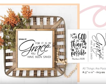 May include: A white sign with black text that reads "For it is by Grace you have been saved" with the scripture reference "Ephesians 2:8". The sign is framed in wood and is sitting on a woven basket with a string of wooden beads. The sign is 8.5 inches by 11 inches and costs $13.99.